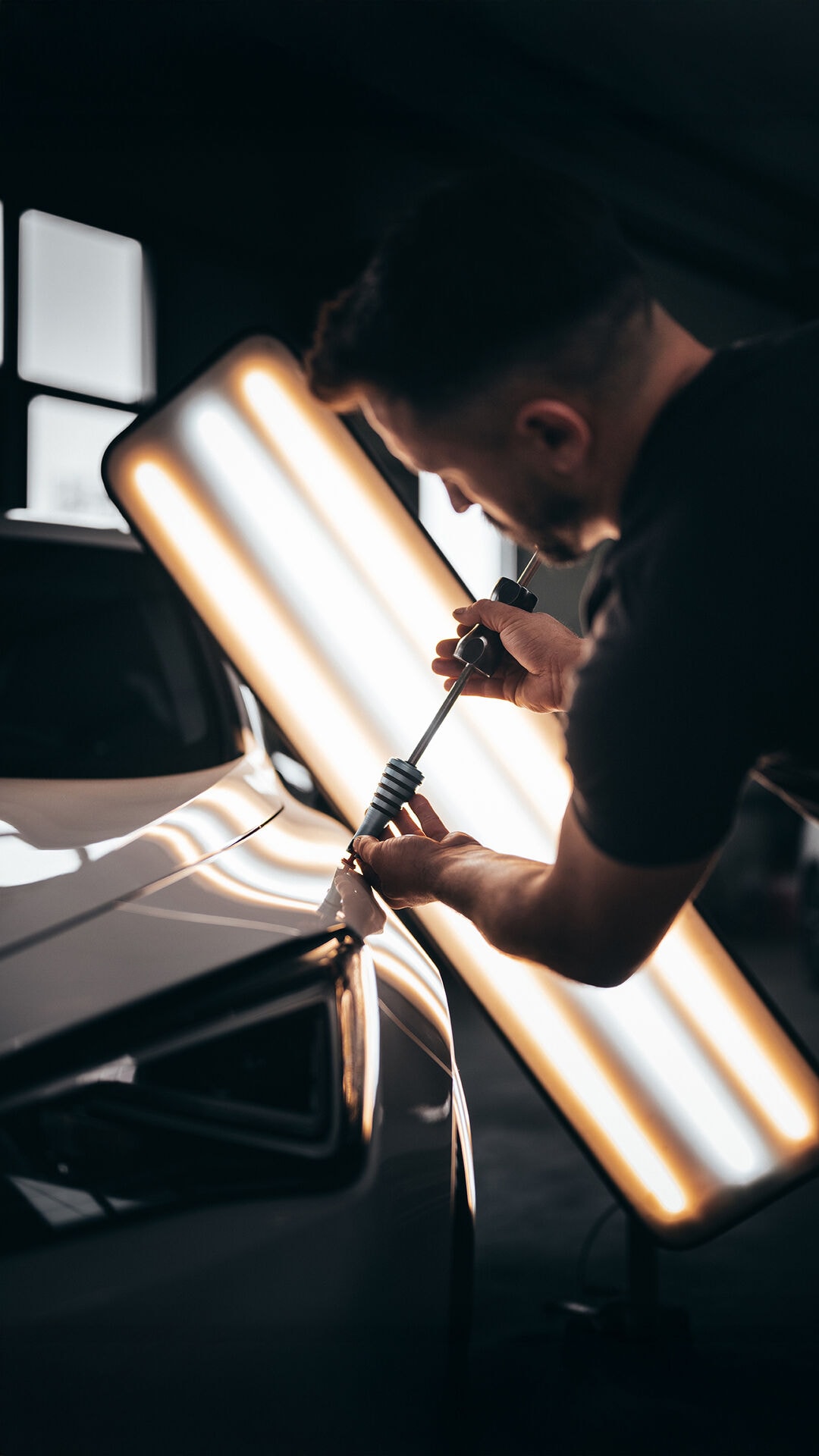 PDR technician repairing dent with precision lighting