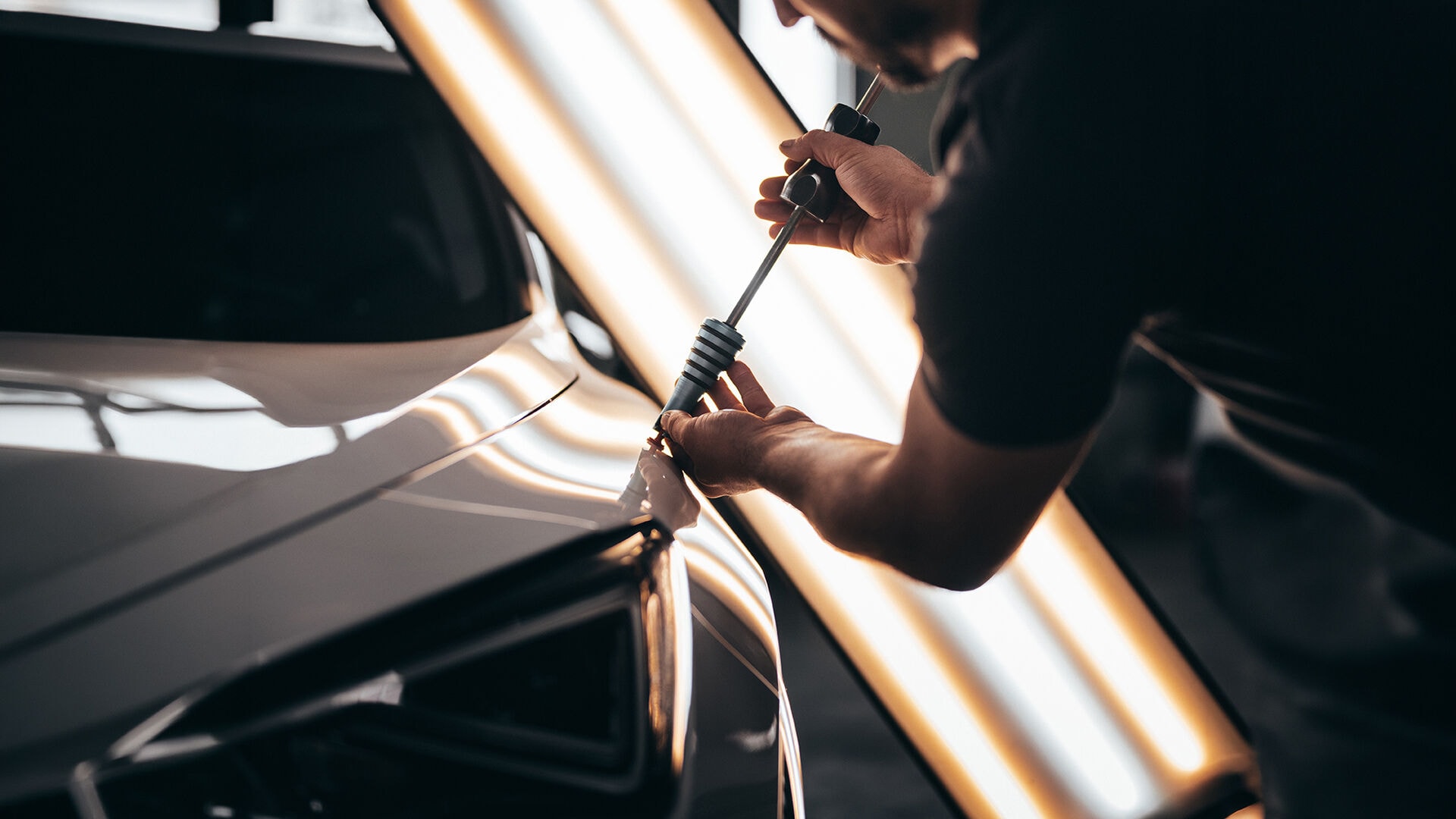 PDR technician repairing dent with precision lighting